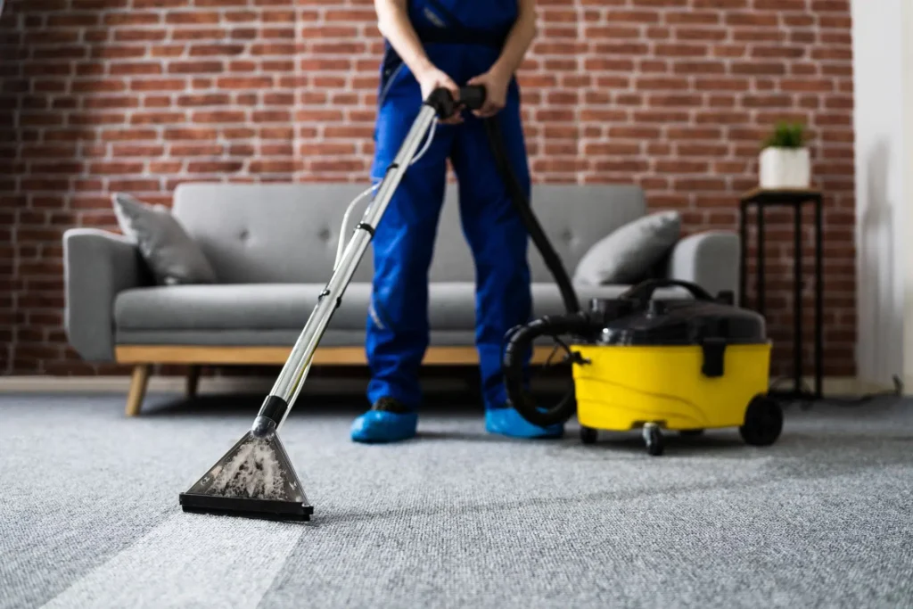 A man is vacuuming a carpeted floor.